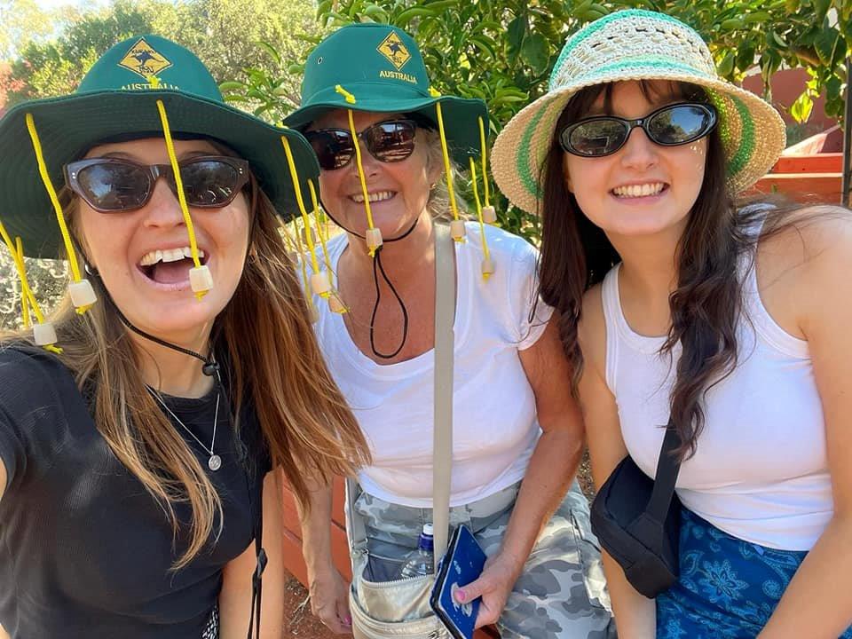 Three women smiling in a selfie, all wearing sunglasses and Australian cork hats.